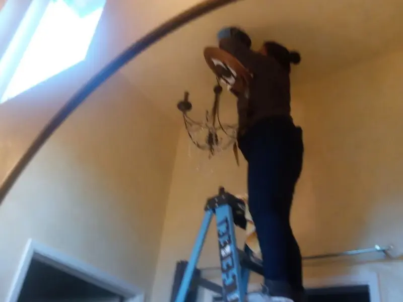 Electrician installing a chandelier in a Peoria Heights residence